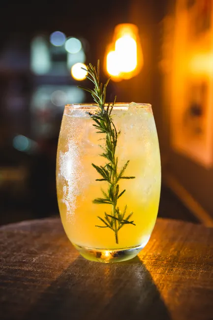 Golden cocktail garnished with a fresh rosemary sprig